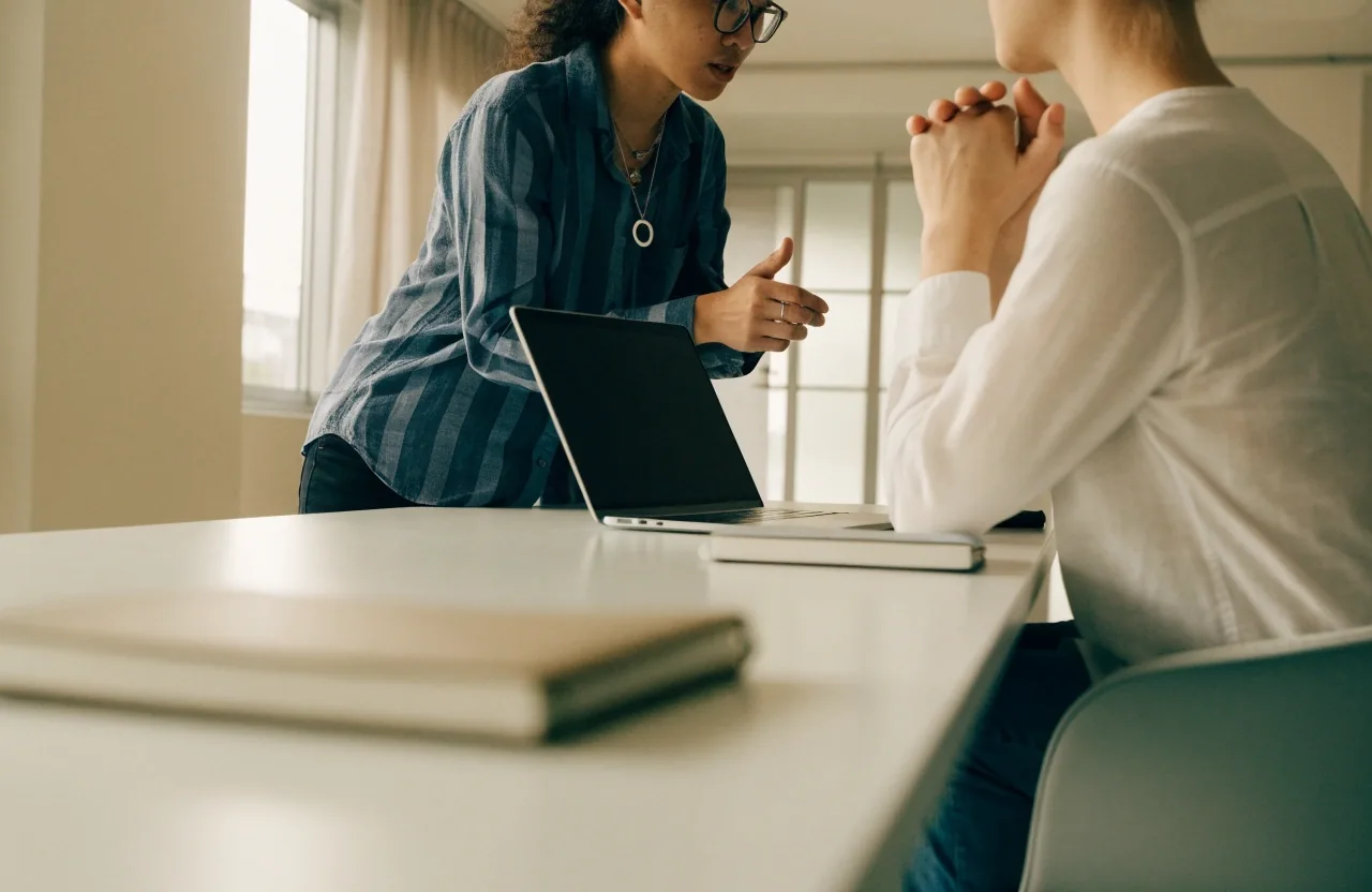 A consultant on a client call seen from behind at a bright studio table